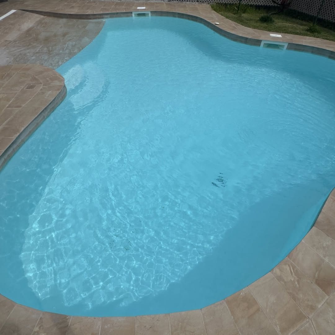 Piscine de forme libre fraîchement cuvelée en gelcoat bleu clair, margelles en pierre